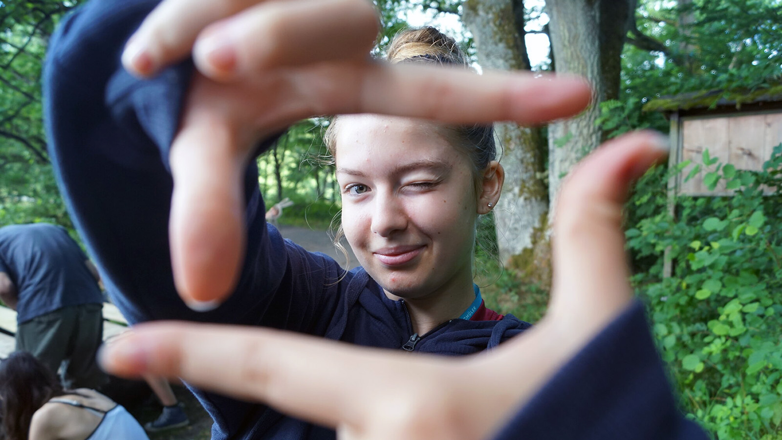 Eine Jugendliche hält ihre Hände zum Zukunftsfenster und blickt hindurch.