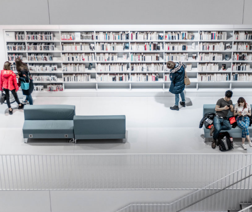 Menschen lesen und stöbern in einer Bibliothek.