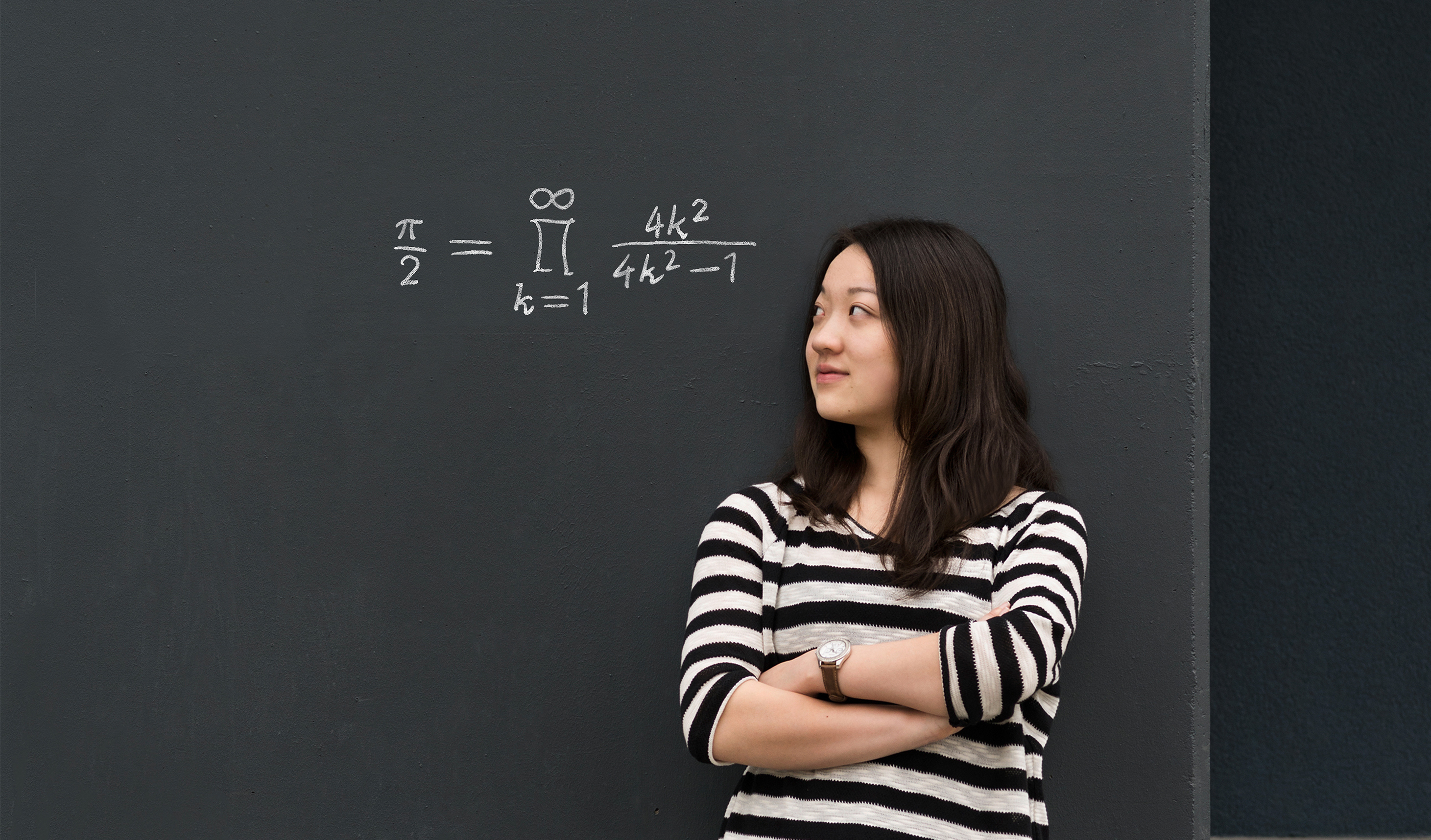 Junge Frau steht vor einer Tafel, auf der eine mathematische Formel steht.