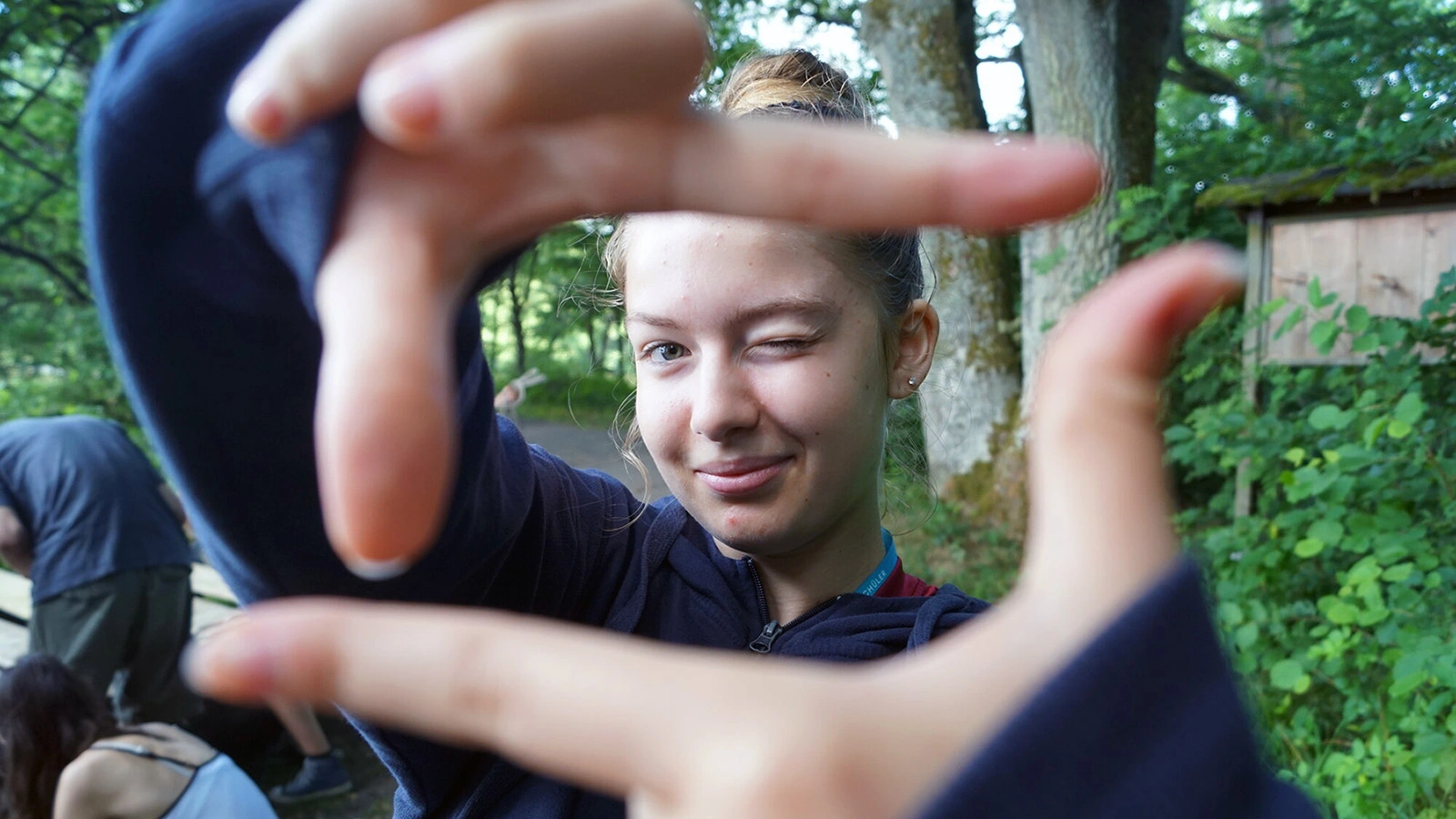 Eine Jugendliche hält ihre Hände zum Zukunftsfenster und blickt hindurch.