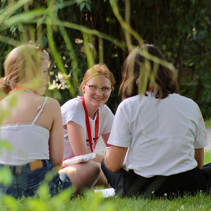 Teilnehmerinnen der Akademie Gaesdonck sitzen entspannt auf einer Wiese.